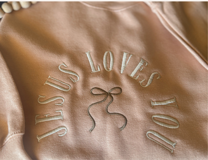 Brown fabric with 'JESUS LOVES YOU' embroidered in white thread.
